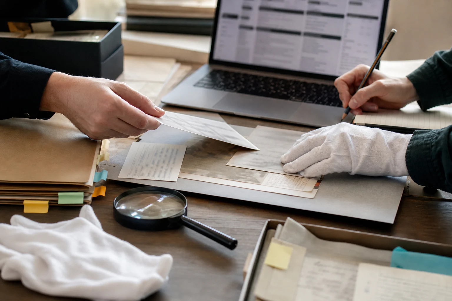Cotton-gloved hands compare archival records and blurred database entries during provenance research